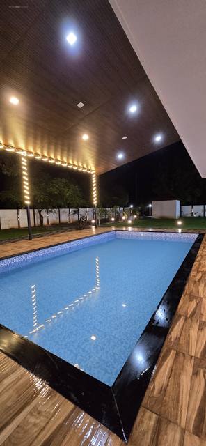 Pool glowing blue at night with palms and warm lights