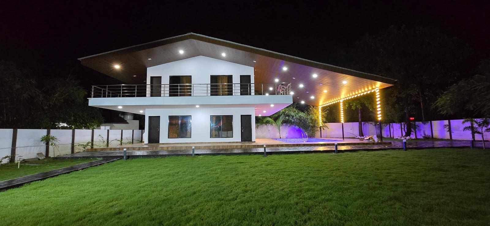 The villa lit up at night with purple and warm lights over the lawn